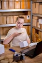 Female small business owner using mobile app on smartphone checking parcel box. Warehouse worker, seller holding phone Royalty Free Stock Photo