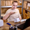 Female small business owner using mobile app on smartphone checking parcel box. Warehouse worker, seller holding phone scanning Royalty Free Stock Photo