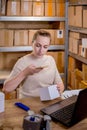 Female small business owner using mobile app on smartphone checking parcel box. Warehouse worker, seller holding phone scanning Royalty Free Stock Photo