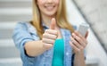 Female with smartphone showing thumbs up