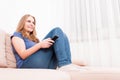 Female smiling relaxing on sofa holding remote control Royalty Free Stock Photo