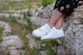 Female sneakers. White female shoes on feet. Sneakers closeup.