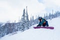 Female snowboarder buttons fastening a snowboard sitting on a snowy slope. Sport.