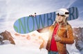Female snowboarder with snowboard in front of a wintry mountain landscape