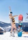 Female snowboarder in swimsuit and flower garland with snowboard on winter mountain ski resort.