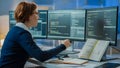 Female software engineer working on multiple monitors with code and system architecture designs in notebook Royalty Free Stock Photo