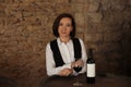 Female sommelier with glass and bottle of red wine