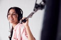 Female Sound Recordist Holding Microphone On Video Film Production In White Studio