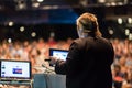 Female public speaker giving talk at Business Event.