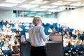 Female speaker giving a talk on corporate business conference. Unrecognizable people in audience at conference hall Royalty Free Stock Photo