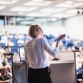 Female speaker giving a talk on corporate business conference. Unrecognizable people in audience at conference hall Royalty Free Stock Photo