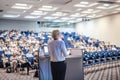 Female speaker giving a talk on corporate business conference. Unrecognizable people in audience at conference hall Royalty Free Stock Photo