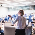 Female speaker giving a talk on corporate business conference. Unrecognizable people in audience at conference hall Royalty Free Stock Photo