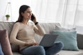Female speaking on mobile phone with client, use laptop for remote work at home, new normal