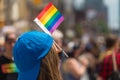A female spectator is watching the gay pride parade with a gay rainbow flag attached to her cap