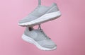 Female sport gray sneakers for run or fitness hanging on pink background