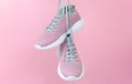 Female sport sneakers for run or fitness hanging on pink background closeup