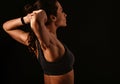 Female sporty muscular with ponytail doing stretching workout of the shoulders, blades in sport bra, holding the hands on the