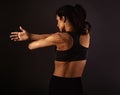 Female sporty muscular with ponytail doing stretching workout of the shoulders, blades in sport bra, holding the hands on the