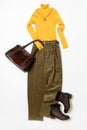 Female spring or autumn stylish clothing set. Yellow sweater and leather boots, green corduroy trousers, handbag. Trendy