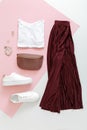 Female spring look summer outfit burgundy skirt white shoes sneakers white basic tshirt waist bag. Folded fly clothes Royalty Free Stock Photo