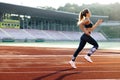 Female sprinter race on outdoor track arena. Female marathon runner on professional sports arena. Fitness woman racing