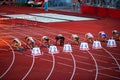 Female Sprinters Lined Up at the Starting Blocks for the 100m Race: Precise Moment Captured on the Athletic Track. Track and field