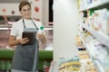 female staff in apron using digital tablet in supermarket holding a bottle of milk in his hands Royalty Free Stock Photo