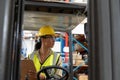 Female staff writing on clipboard while sitting on forklift