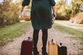 Female standing on an empty road  near her old suitcase while holding the bible and a desk globe Royalty Free Stock Photo