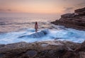 Female standing on shipwreck rock with ocean awash flowing over it