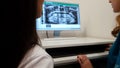 Female stomatologist showing patient teeth x-ray image on computer, diagnosis