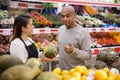 Female store employee helping man choosing fruits in supermarket