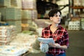 Female storekeeper checks availability of goods with documents in the building materials warehouse