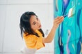 Female street artist painting colorful graffiti with paintbrushe on wall