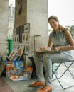 Female street artist paints and sells her work in Paris
