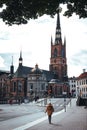 Female strolls along a cobblestone street in front of the Riddarholmen Church in Stockholm, Sweden