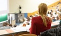 Female student attending faculty lecture workshop making notes.