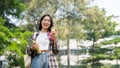 A female student carrying her backpack, digital tablet, and a coffee cup standing in a campus park Royalty Free Stock Photo