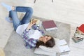 Female student checking social media before getting back to studying, lying on floor against cozy domestic interior