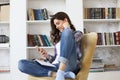 Female student checking social media before getting back to studying, sitting on floor against cozy domestic interior