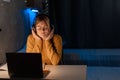 Female student at desk in dorm at late night listening music using laptop computer and headphones. Royalty Free Stock Photo