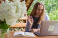 Female student has online lesson education outdoor in garden wooden alcove. Blonde woman sitting outside work on laptop