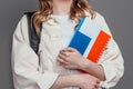 female student holding backpack, book, notebook, passport isolated on a dark grey background