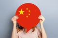 Female student holds blank white speech bubble with Chinese flag isolated over grey studio background