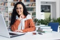 Female student with laptop reading online video course, Latin American woman smiling and satisfied with independent Royalty Free Stock Photo