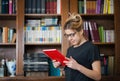 Female student in a library with book in hands Royalty Free Stock Photo