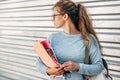 Female student looking back and carrying lots of books after a day in the college. Pretty young woman wearing a blue sweater and Royalty Free Stock Photo