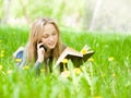 Female student lying on grass reading a book and talking on the green grass Royalty Free Stock Photo