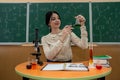 female student is practicing in a chemistry classroom with flasks on of a board with formulas. Royalty Free Stock Photo